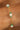 Close-up of a gold chain bracelet with pearls and green beads on a wrist.