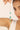 Jewelry with green stones and gold chain held by a hand against a blurred background