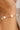 Gold bracelet with pearls on a wrist against a neutral background