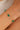 Gold bracelet with green beads on a wrist against a neutral background