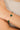 Gold bracelet with green gemstones on a wrist against a neutral background