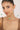 Woman wearing a gold necklace with green gemstones against a neutral background
