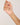 Hand holding a delicate gold necklace with small colored beads against a plain background