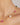 Gold necklace with pink and white beads on a woman's neck against a neutral background