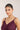 Woman wearing a purple dress and gold necklace against a plain background