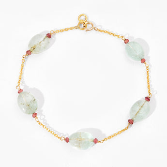 Gold bracelet with white and red beads on a white background