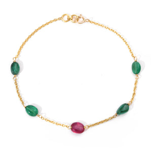 Gold bracelet with green and red gemstones on a white background