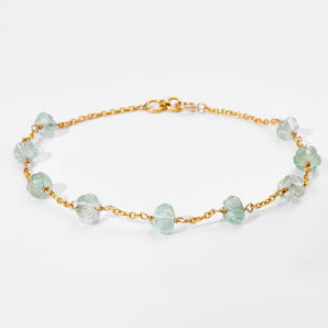 Gold bracelet with white gemstones on a light gray background