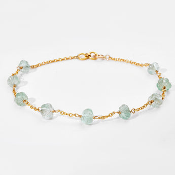 Gold bracelet with white gemstones on a light gray background