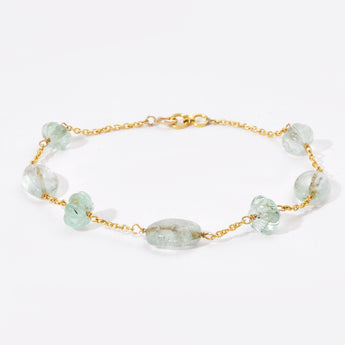 Gold bracelet with green gemstones on a white background