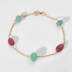 Bracelet with gold chain and green and pink beads on a white background