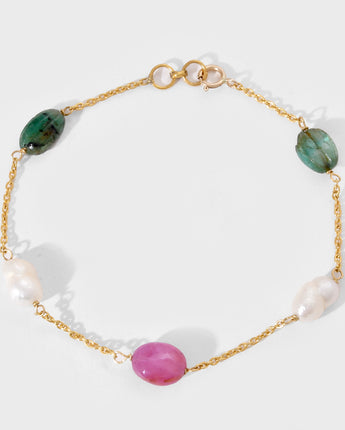 Bracelet with gold chain, green, pink, and white gemstone on a white background