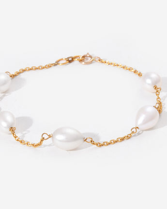 Pearl bracelet with gold chain on a white background