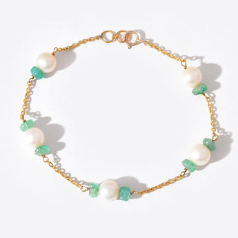Gold bracelet with pearls and green beads on a white background