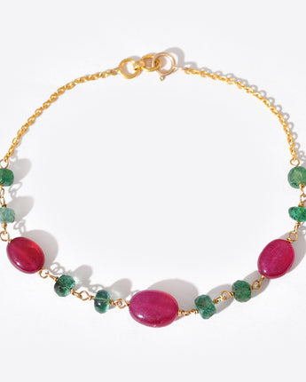 Bracelet with pink and green gemstones on a gold chain against a white background