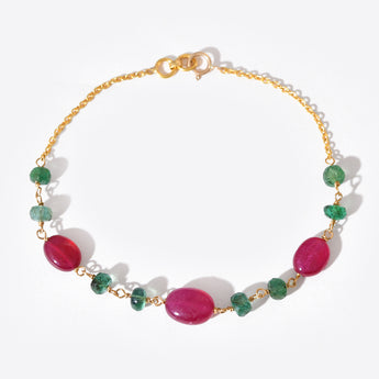 Bracelet with pink and green gemstones on a gold chain against a white background