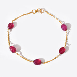 Gold bracelet with red gemstones on a white background
