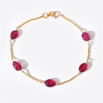 Gold bracelet with red gemstones on a white background