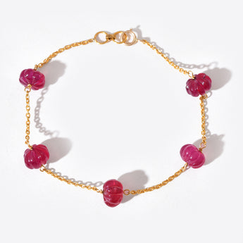 Gold bracelet with red beads on a white background