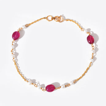 Bracelet with gold chain, white beads and pink stones on a white background