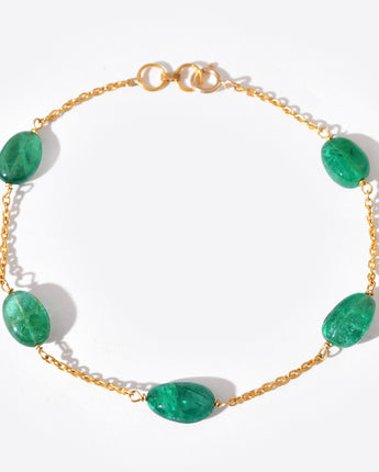 Gold bracelet with green gemstones on a white background