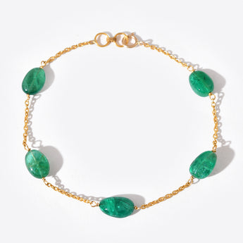 Gold bracelet with green gemstones on a white background
