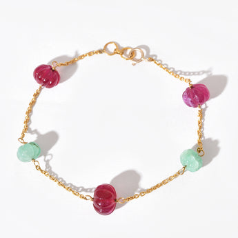 Bracelet with pink and green beads on a gold chain against a white background