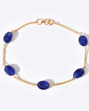 Gold bracelet with blue gemstones on a white background