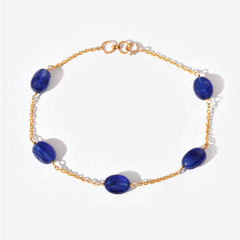 Gold bracelet with blue gemstones on a white background