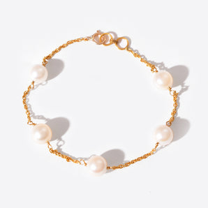 Gold chain bracelet with pearls on a white background