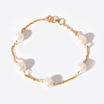 Gold chain bracelet with pearls on a white background