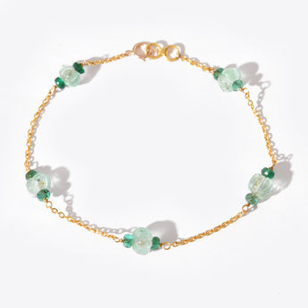 Gold bracelet with green gemstones on a white background