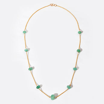 Necklace with green gemstone on a gold chain against a white background