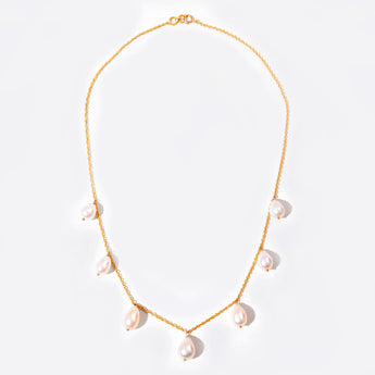 Gold necklace with pearl drops on a light background
