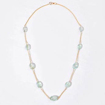 Necklace with white gemstone on a gold chain against a white background