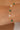 Gold bracelet with green gemstones and pearls on a wrist against a beige background