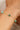 Gold bracelet with green gemstones on a wrist against a neutral background