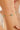 Gold bracelet with green beads on a wrist against a neutral background