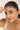 Woman holding a bracelet on her face with a plain background