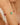 Close-up of a person's arm wearing a gold bracelet with green and red beads.