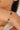 Gold bracelet with green stones on a wrist against a neutral background