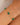 Gold bracelet with green beads on a wrist against a neutral background