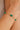 Gold bracelet with green gemstones on a wrist against a neutral background