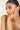 Woman touching her face wearing a delicate bracelet with a neutral background
