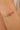 Gold bracelet with pink and green beads on a wrist