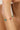 Gold bracelet with colorful beads on a wrist against a neutral background