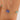 Gold bracelet with a blue and green bead on a wrist against a neutral background