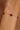 Gold bracelet with red beads on a wrist against a blurred background
