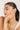 Woman touching her face wearing a delicate bracelet with a neutral background