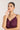 Woman wearing a purple dress and green necklace against a plain background